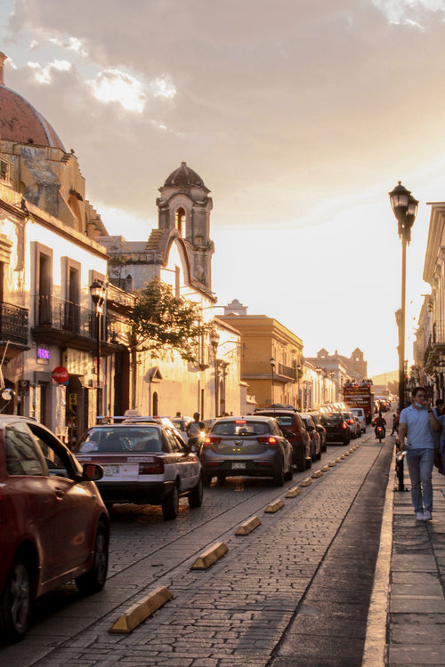 Free Traffic and historic architecture in Oaxaca de Juárez at sunset, showcasing vibrant urban life. Stock Photo