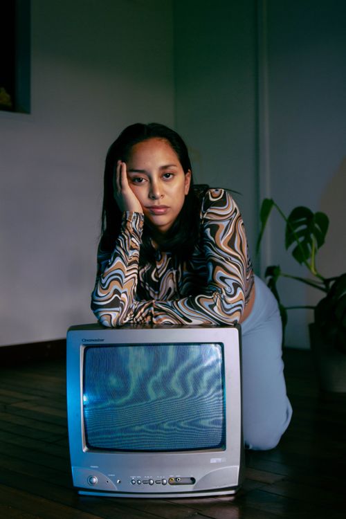 Free Woman leaning on a vintage TV in a stylish indoor setting, evoking nostalgia. Stock Photo