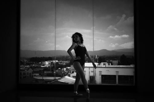 Free A ballerina poses elegantly by a large window overlooking an urban landscape in Lerma de Villada, Mexico. Stock Photo