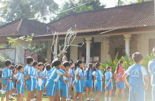 Children gathered in sports uniforms for outdoor school activities by a traditional building. - Fotografer Sidoarjo