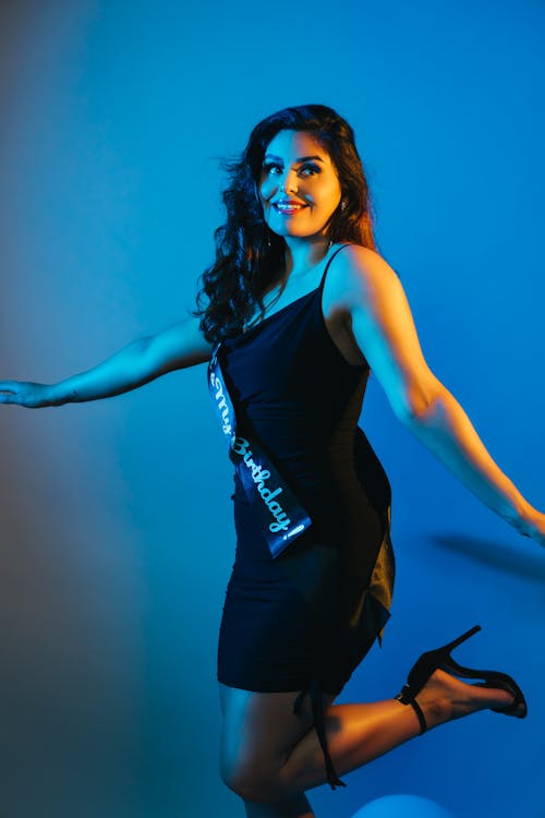 Young Woman in a Black Dress and High Heels Posing in Studio 