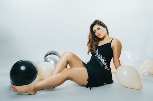 Woman in a Dress and a Birthday Sash Sitting on the Floor with Balloons