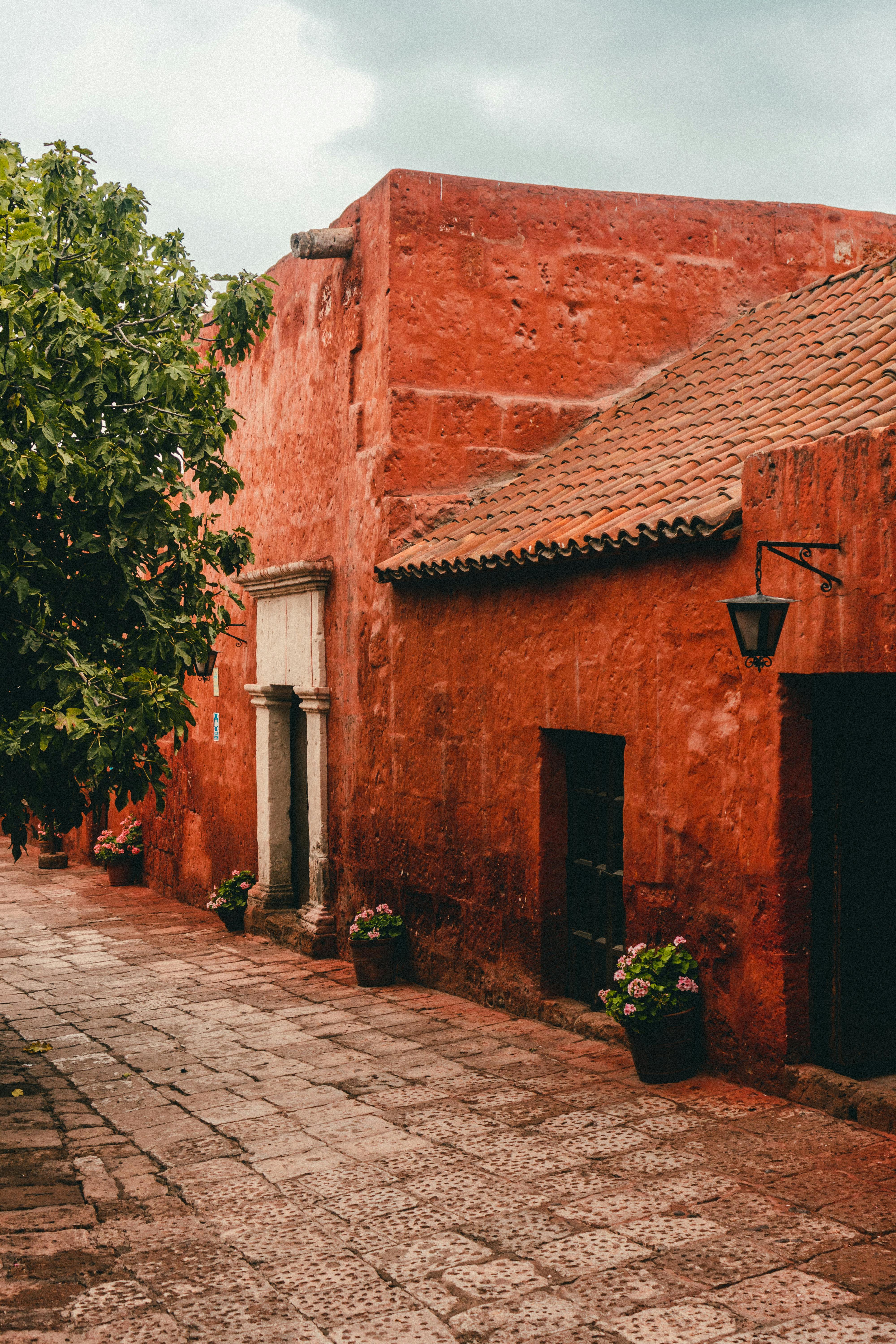 Charming red adobe building in Arequipa with cobblestone street, capturing cultural essence and colonial architecture.
