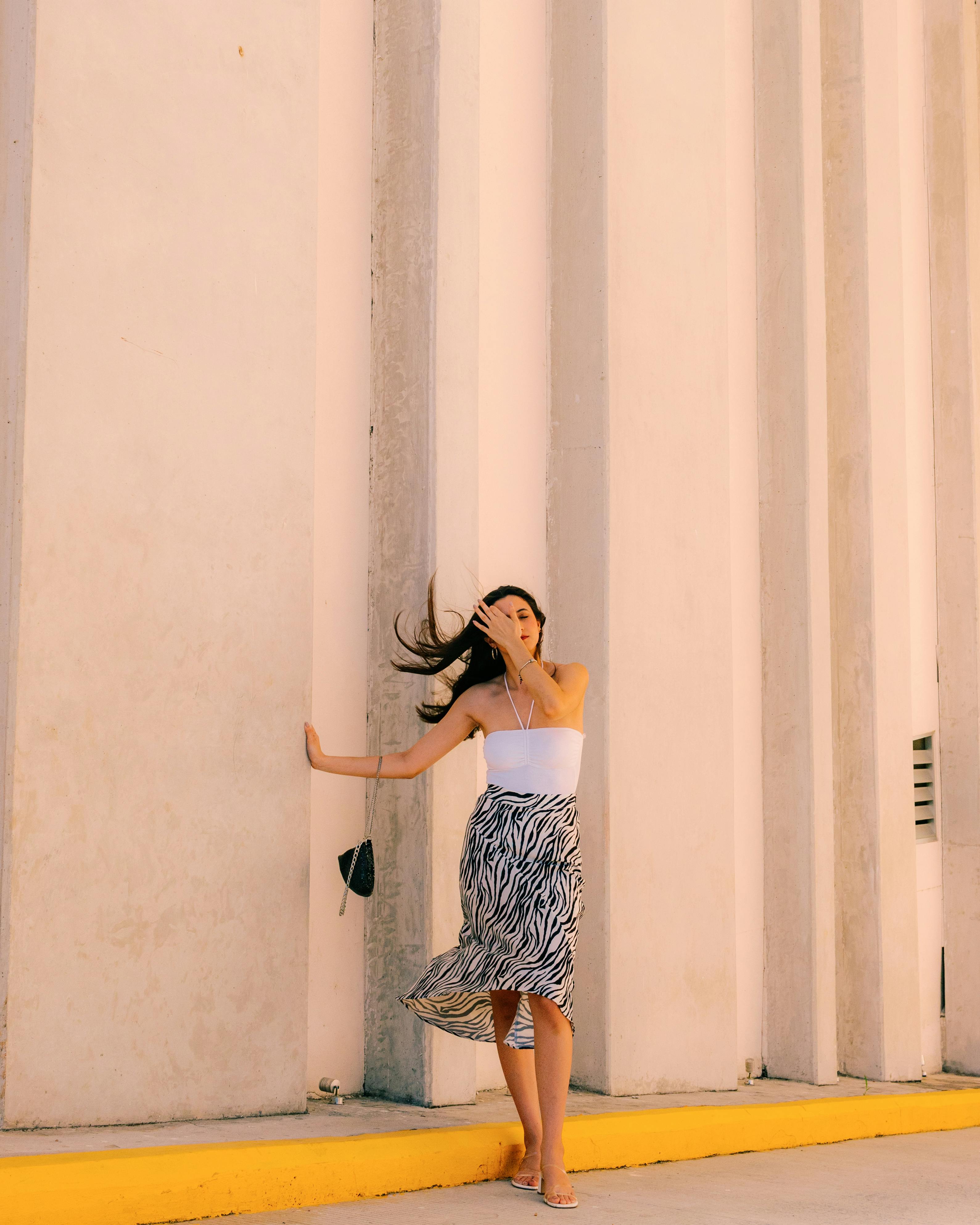 Woman in stylish summer dress posing against a modern architectural wall in Mérida, Mexico.