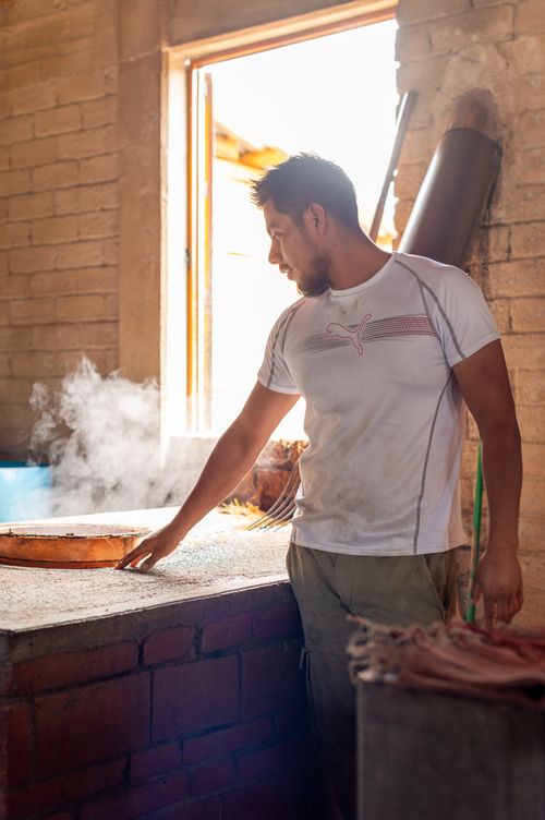 Free A man stands in a rustic kitchen, cooking with steam rising around him. Stock Photo
