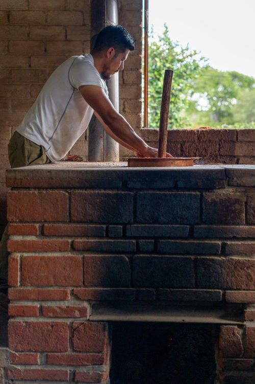 Free A worker prepares mezcal in a rustic Mexican distillery with brick structures. Stock Photo