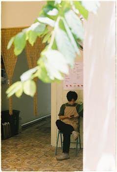 A young man sits indoors, enjoying a moment of relaxation in a cozy café environment.
