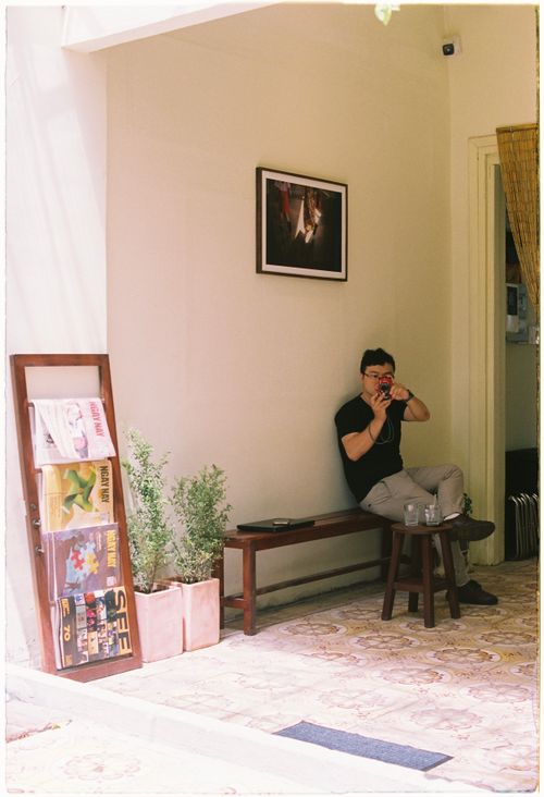 Free A man sits in a modern café, capturing moments with a camera, embodying relaxation and tranquility. Stock Photo