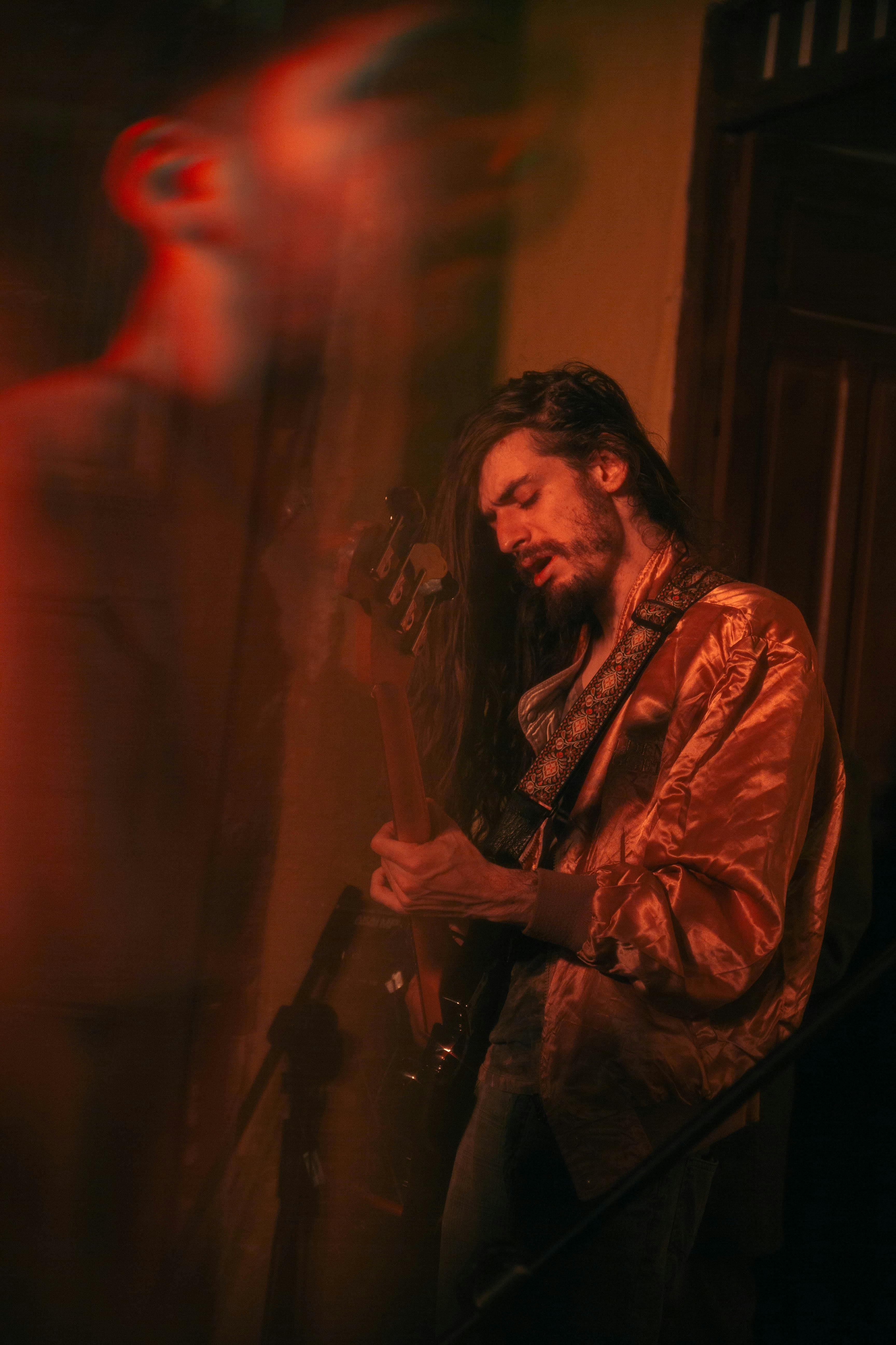 Musician passionately playing guitar under dramatic lighting, adding an artistic and blurred effect.
