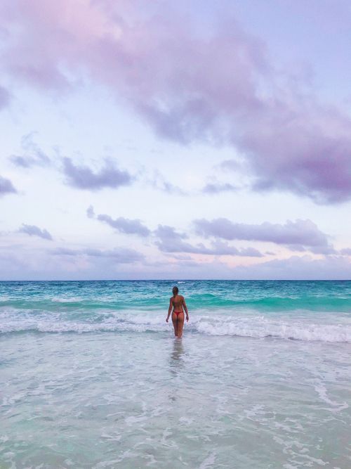 Free Woman enjoying a tranquil moment at the Tulum beach with vibrant ocean waves. Stock Photo