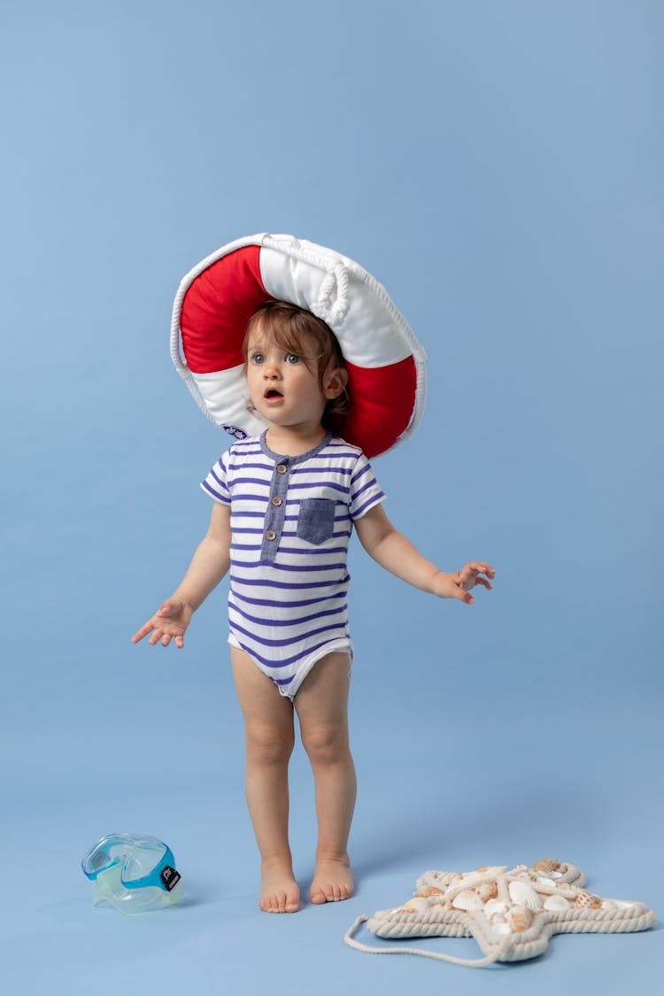 A Little Girl In A Swimming Costume Wearing A Pillow Lifebuoy On Her Head