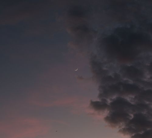 Free A serene twilight sky featuring a crescent moon and dark clouds, perfect for contemplative ambiance. Stock Photo