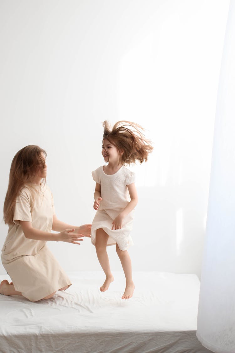 Mother And Daughter Jumping On The Bed 