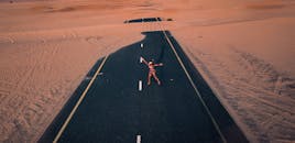 在迪拜的沙漠公路上空，一位戴着圣诞老人帽子的女性俯瞰着下方，画面形成了充满活力的对比