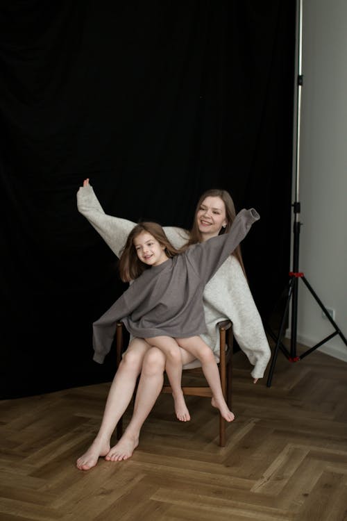 Mother and Daughter Sitting on a Chair and Spreading Their Arms · Free ...