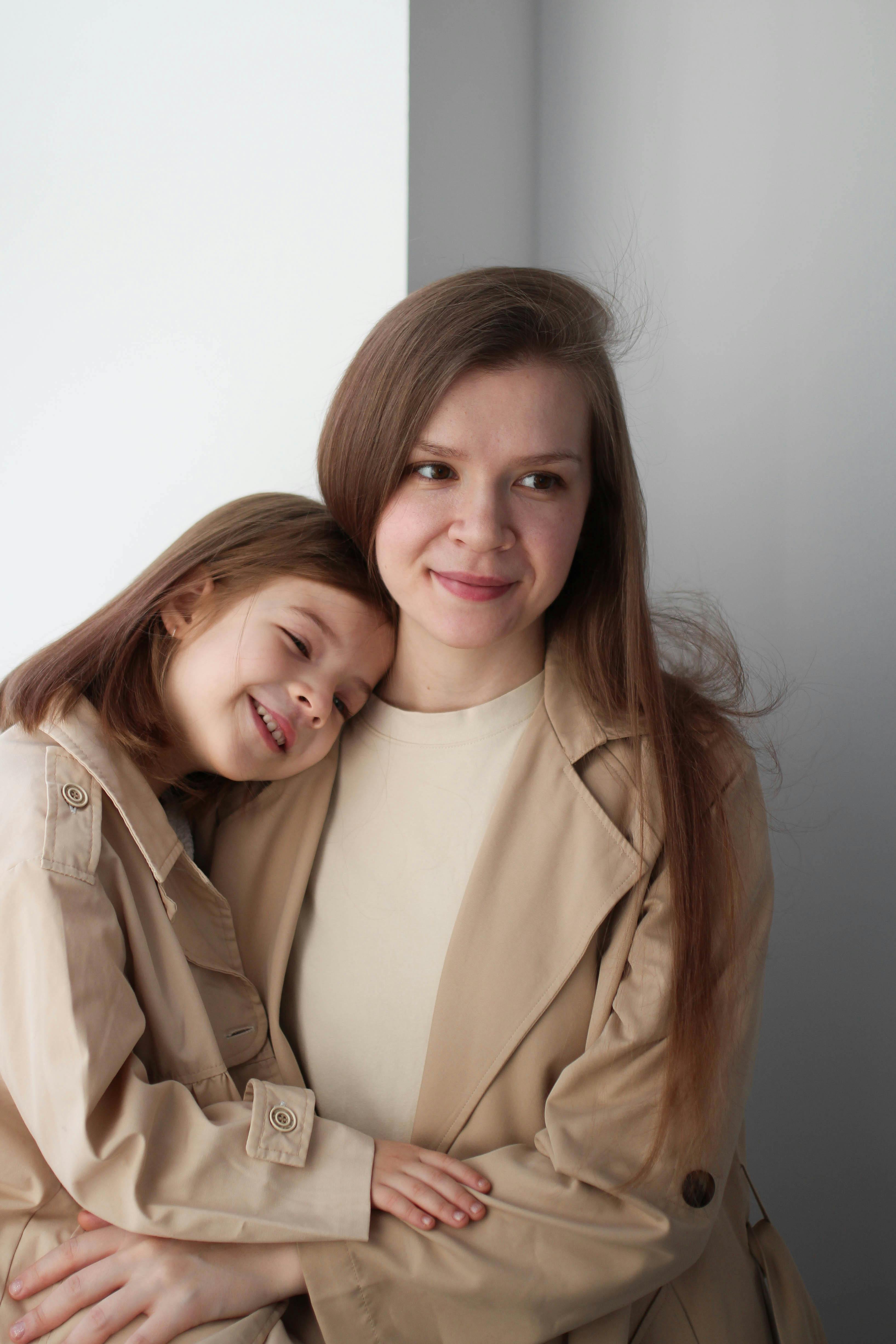 a teenage girl hugging a younger girl