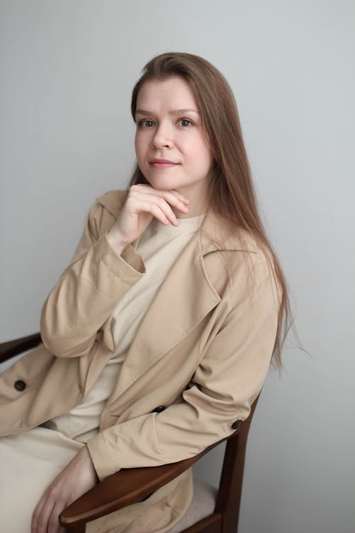 Portrait of a Woman Wearing Beige Coat Sitting on a Wooden Chair