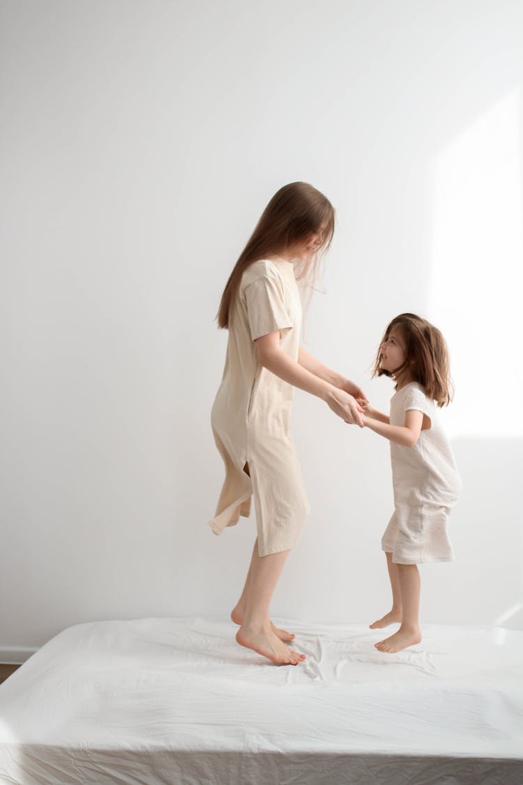 Mother And Daughter Jumping Together On A Bed