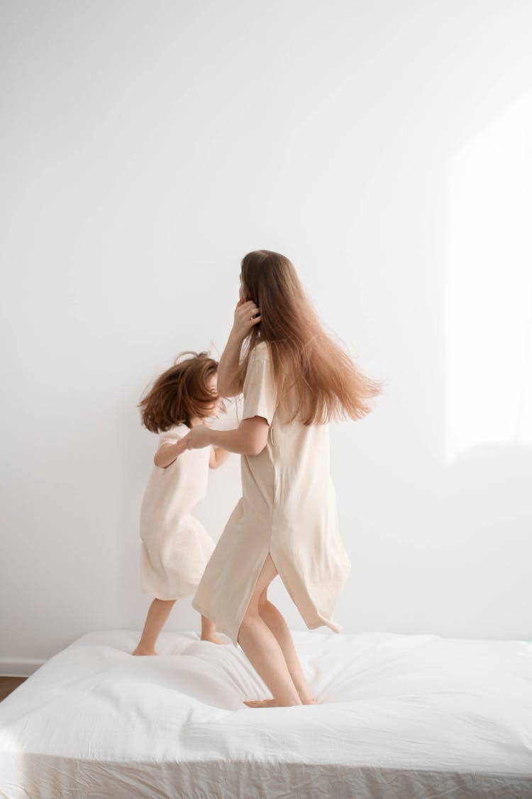 Two Girls Jumping On A Bed