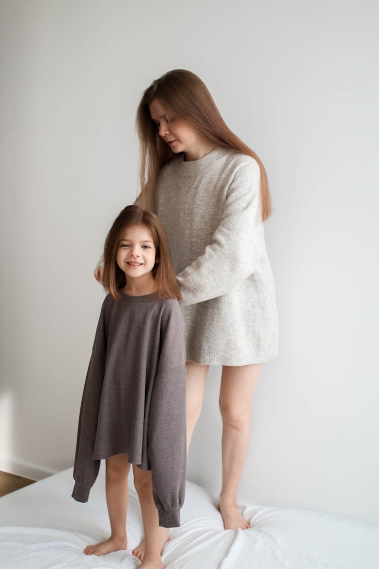 Woman Dressing Her Daughter In An Oversized Jumper