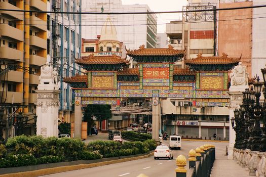 A vibrant and decorative gate marking the entrance to Chinatown in a busy city street setting.