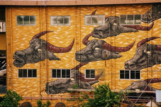 Colorful mural of buffalo heads on a city building showcases vibrant urban art.