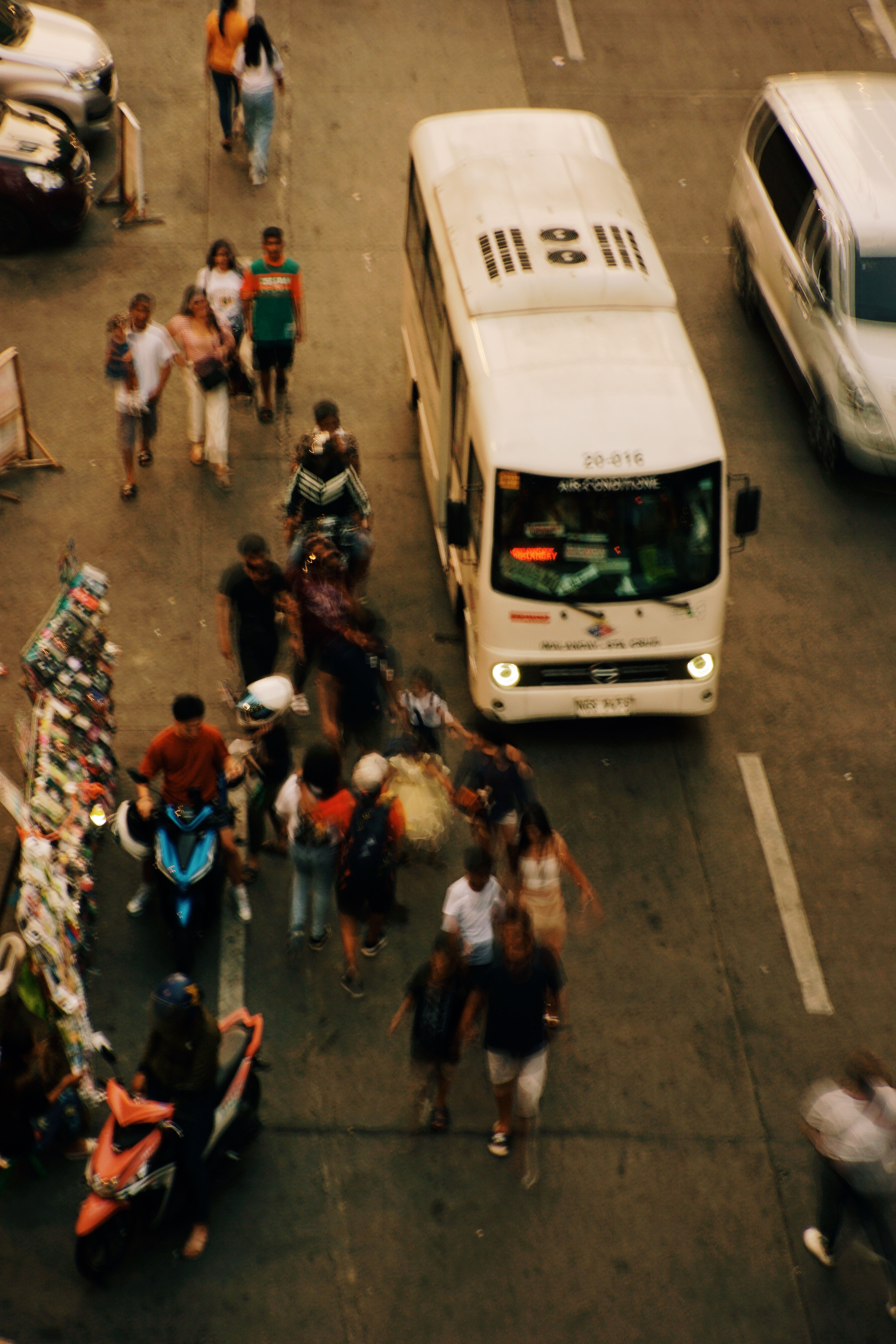 Aerial view of a bustling city street scene with pedestrians and vehicles in motion.