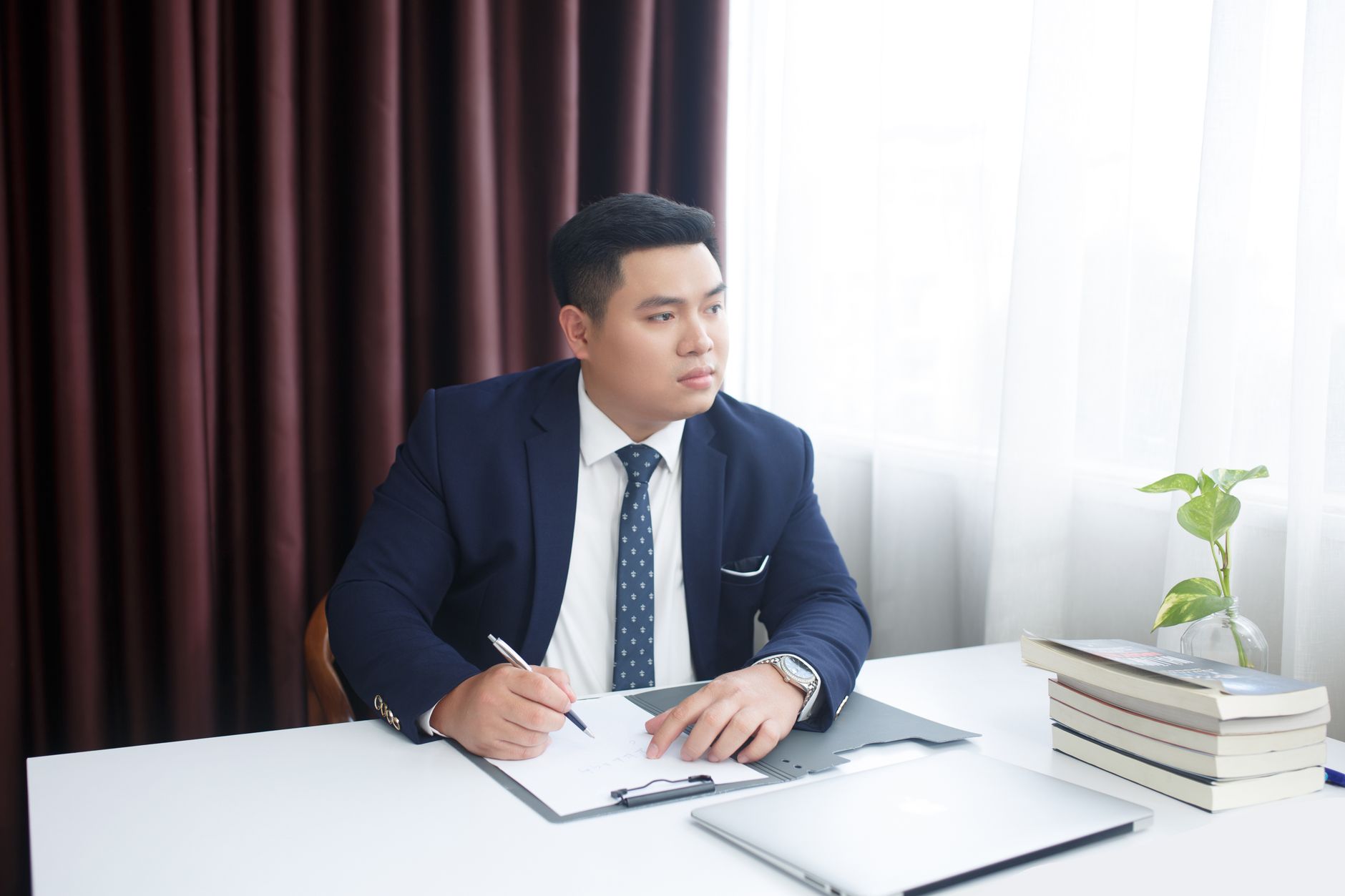 Chuyên viên tài chính đối chiếu bảng doanh thu, tiền hoàn trả và chi phí pháp lý trên máy tính