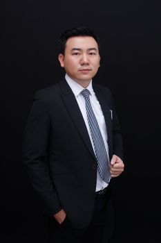 Elegant portrait of a confident businessman in a suit with a black background.
