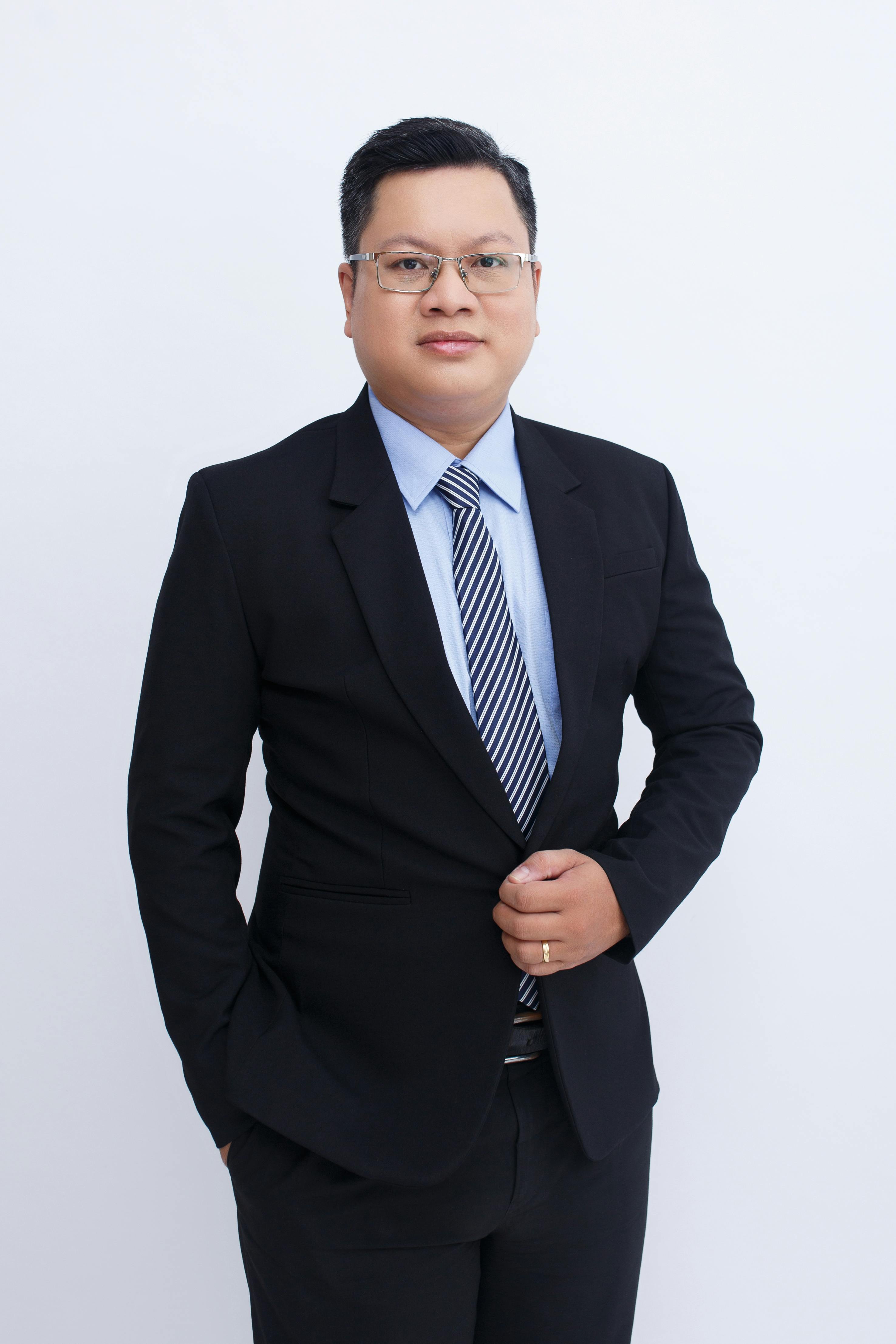 Confident businessman wearing a suit and tie, posing elegantly in a studio setting.