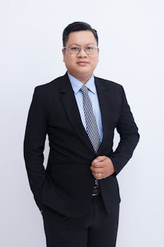 Confident businessman wearing a suit and tie, posing elegantly in a studio setting.