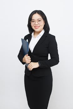 Confident businesswoman smiling in a studio setting, holding documents in a modern fashion.