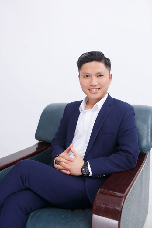 Free Portrait of a smiling businessman in a blue suit seated comfortably on a chair. Stock Photo