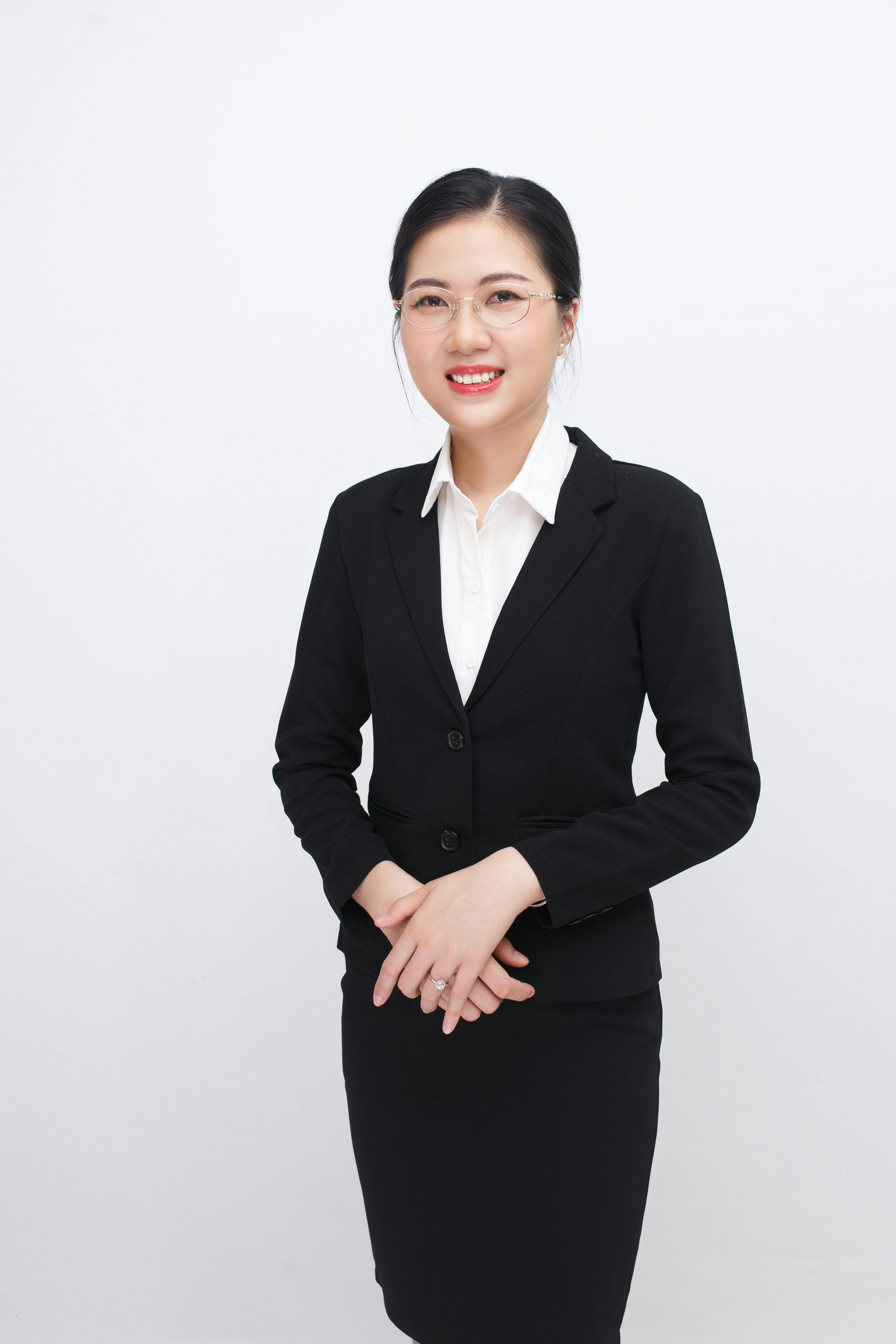 Elegant businesswoman in formal attire, smiling confidently in a studio setting.