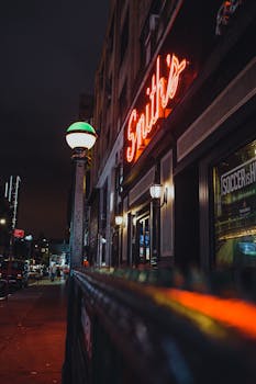 Street view of a bustling urban area at night, featuring neon signs and dimly lit atmosphere.