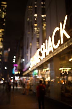 A bustling urban street scene at night featuring illuminated signage and blurred figures.
