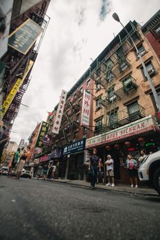 在多云的天空下，唐人街的动态街景展示了不同的商店和行人