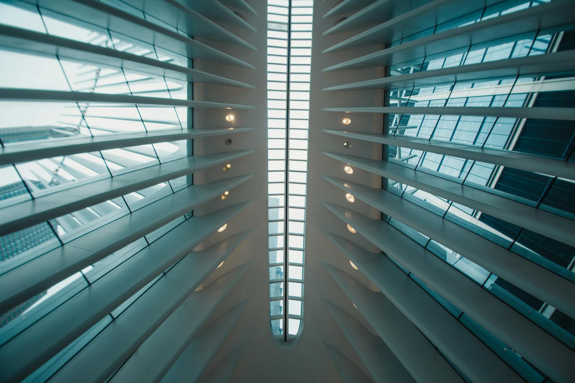 Low angle view of modern futuristic skylight with glass panels and steel beams indoors.