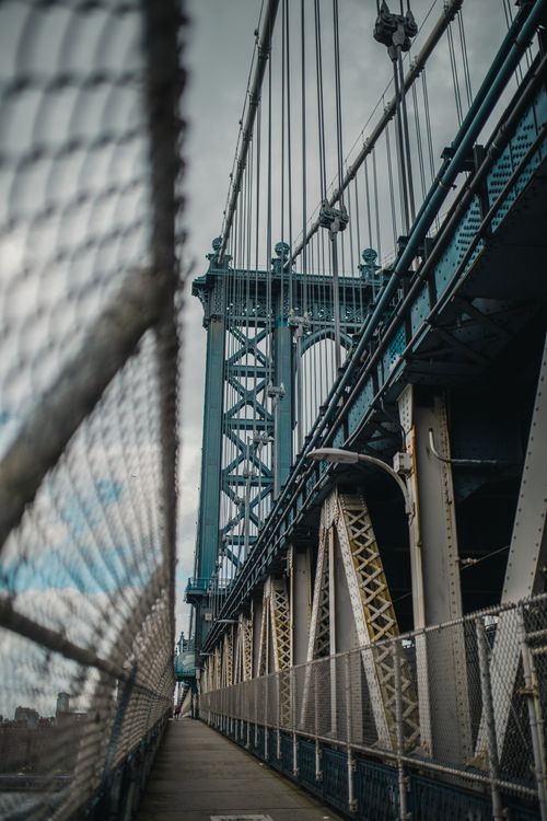 Free Detailed shot of a steel suspension bridge with a wire fence foreground. Stock Photo