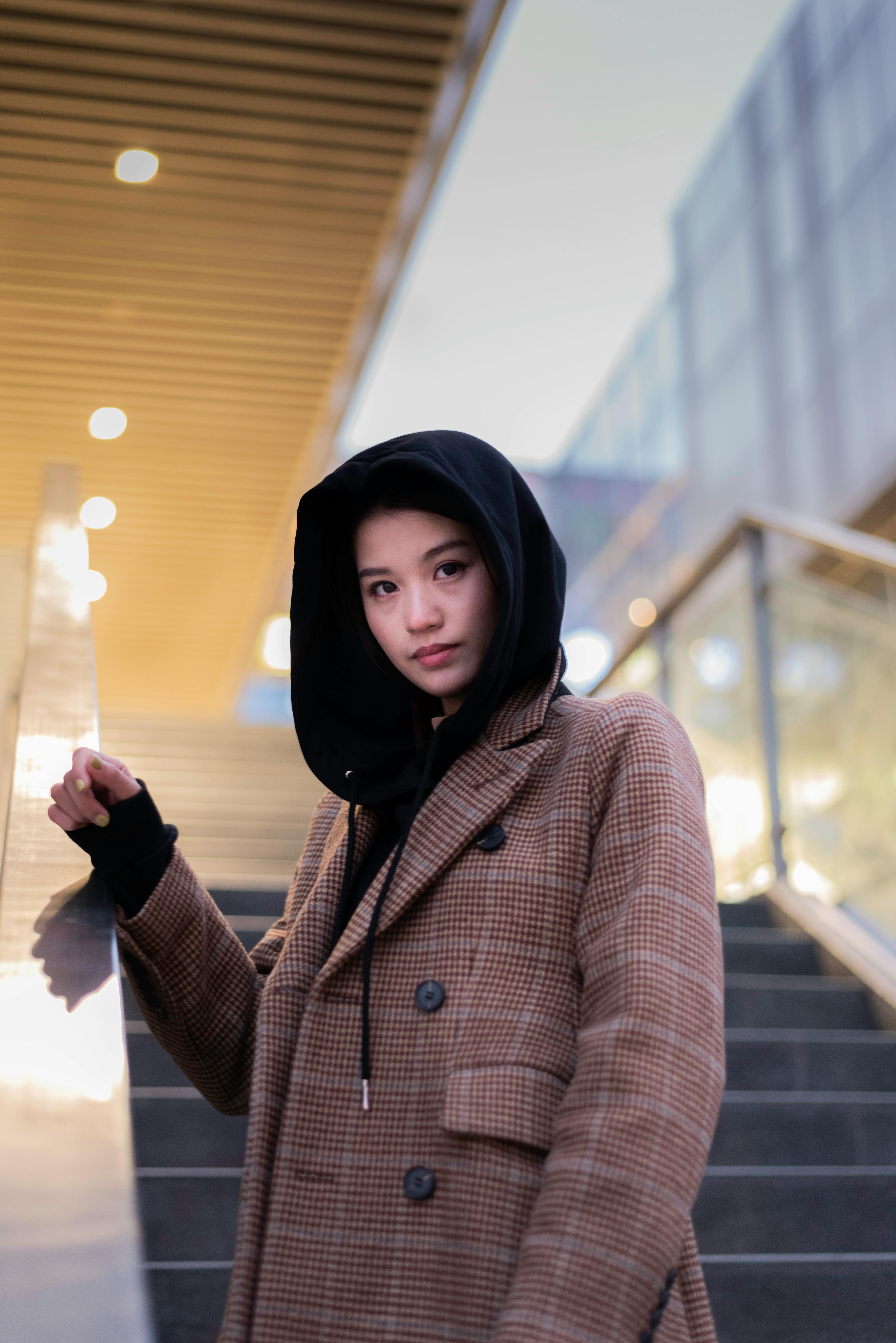 在现代城市环境中，一位年轻女子穿着格纹外套和引擎盖