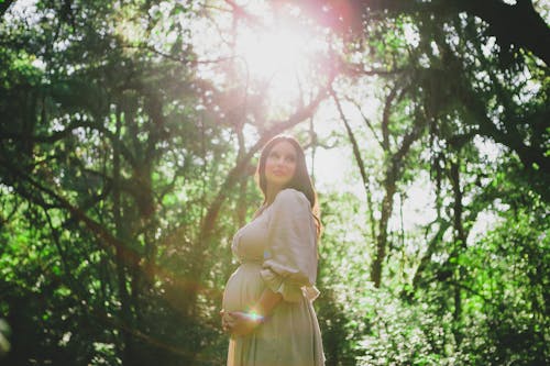 A Pregnant Woman in a Dress Posing in the Forest 