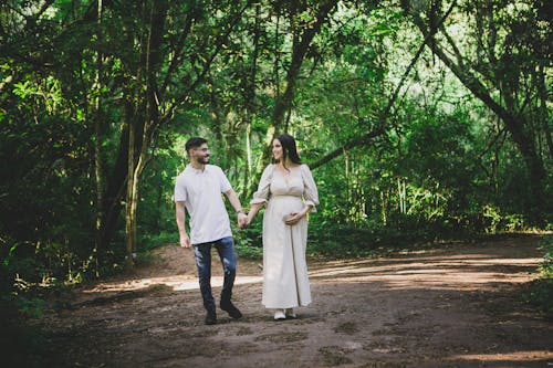 Pregnant Woman Walking with Her Partner and Holding Hands 