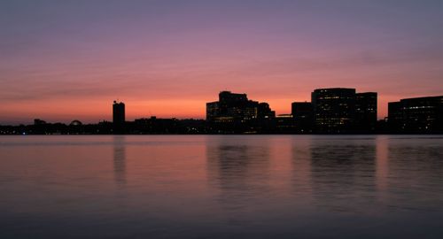 Free A serene cityscape captured at twilight with reflections in the water, showcasing an urban skyline silhouetted against a colorful sky. Stock Photo