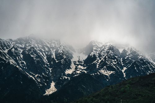Free Majestic snow-covered mountains shrouded in mist and clouds, creating a dramatic landscape. Stock Photo