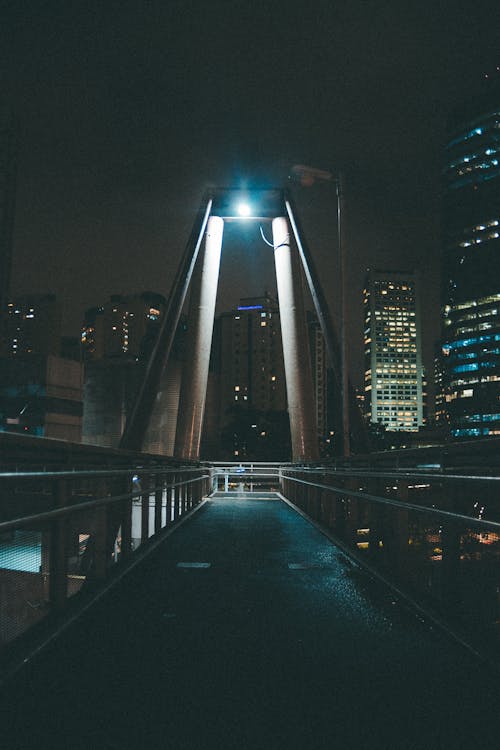 Free Puente Gris Cerca De Los Edificios De La Ciudad Con Luces Encendidas Cerca De Noche Stock Photo