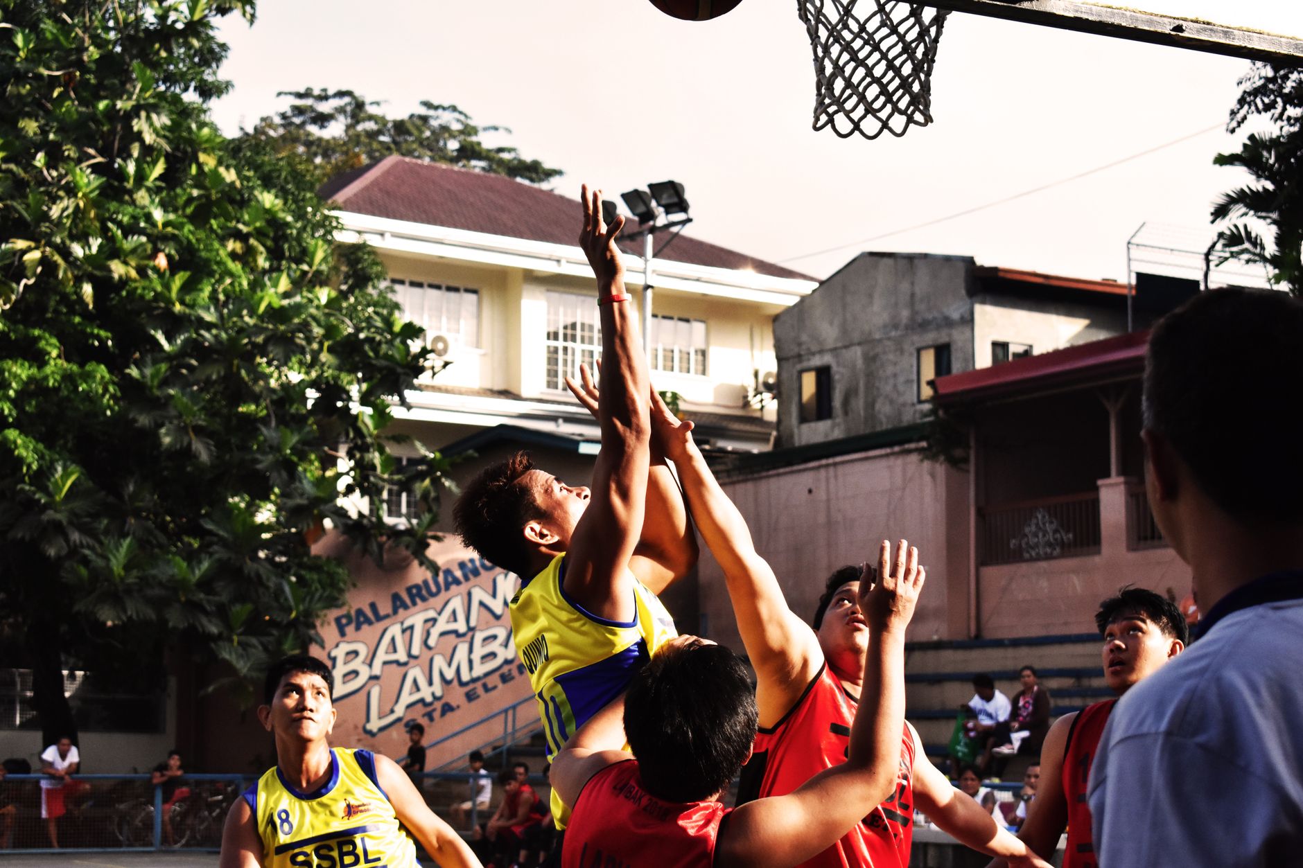 NCAA Basketball photo featuring A group of young adults energetically playing an outdoor street basketball game.