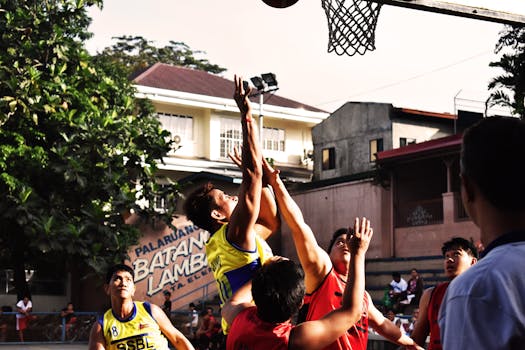 A group of young adults energetically playing an outdoor street basketball game.
