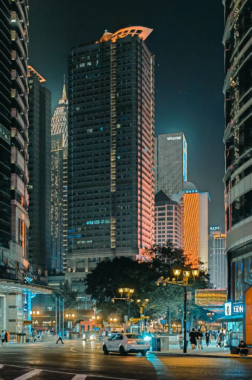 Free A bustling urban street at night with illuminated skyscrapers and vibrant city life. Stock Photo