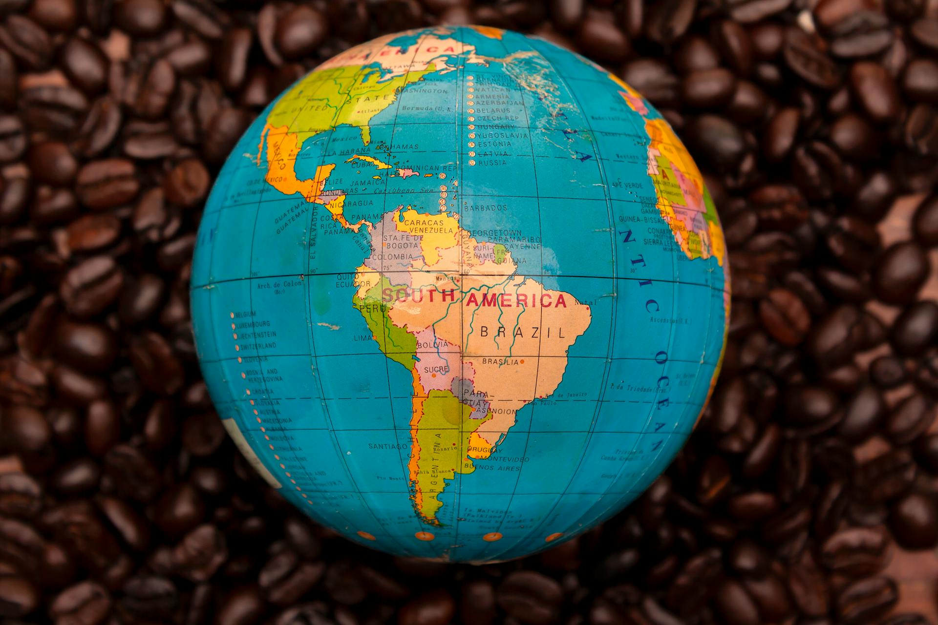 Close-up of South American globe encircled by rich coffee beans, emphasizing geography and culture.