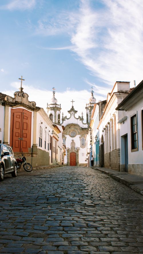 Free Street view of the Nossa Senhora do Carmo Church in São João del Rei, Brazil, with colonial architecture and cobblestone pathway. Stock Photo
